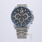 From the Men’s Essential Collection. A perfect blend of precision and design, this dashing chronograph is inspired by racing, hinting at a dashboard in its embossed dial with metallic elements and bright accents. Crafted of stainless steel, with secure screwdown caseback and blue ion-finish tachymeter bezel. The blue multi-layered dial, with orange accents, features LumiBrite hands and 12 o’clock marker, a date calendar and three subdials, one a 24-hour indicator.